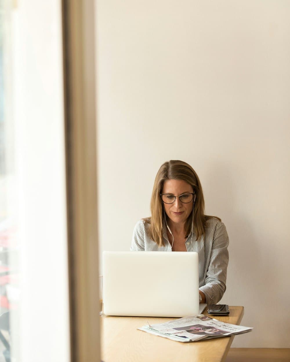 A woman working on a laptop at a wooden table