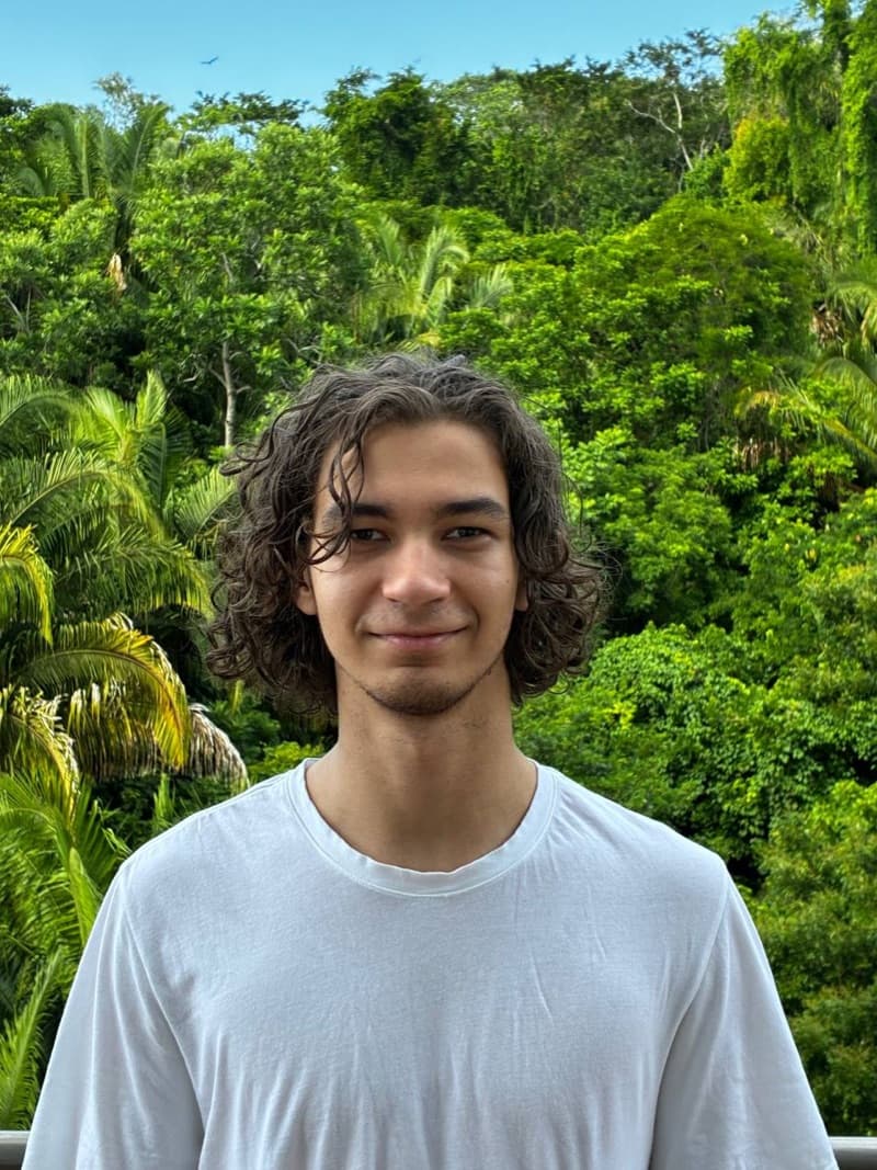 Edward Korytskyi, founder of Elegix, smiling in a white T-shirt in front of tropical greenery