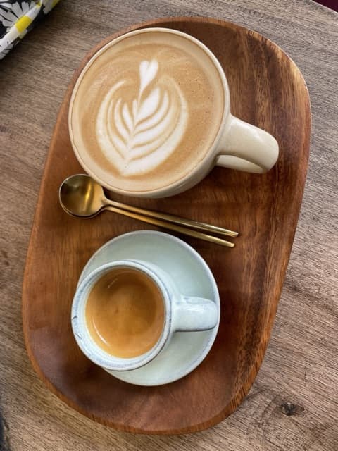 Two cups of coffee on a wooden tray, seen from above